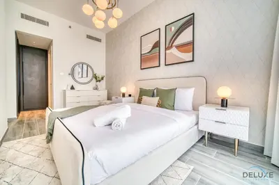 a bedroom with a large white bed in a room at Placid 2BR with Assistant Room at Mesk 1 Midtown Dubai Production City by Deluxe Holiday Homes in Dubai