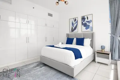 a white bedroom with a large bed with blue accents at Luxury 2BR with Breath-taking Dubai Marina Views in Dubai