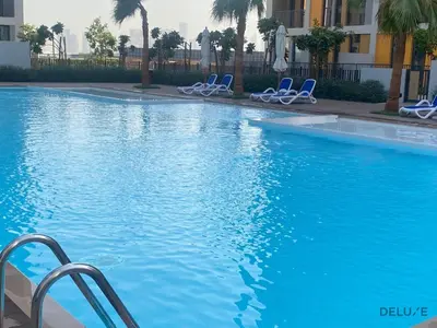 a swimming pool with blue chairs in a building at Impressive 2BR with Assistant Room at Mesk 1 Midtown Dubai Production City by Deluxe Holiday Homes in Dubai