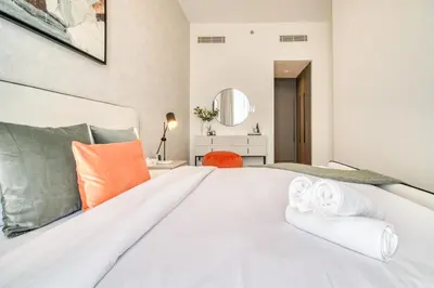 a bedroom with a large white bed with orange pillows at Alluring 2BR with Assistant Room at Mesk 1 Midtown Dubai Production City by Deluxe Holiday Homes in Dubai