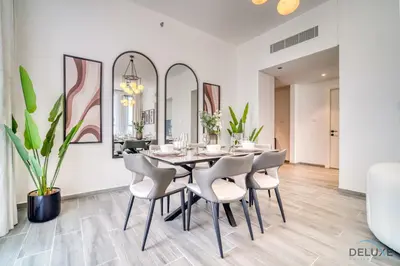 a dining room with a table and chairs and mirrors at Harmonious 2BR with Assistant Room at Mesk 1 Midtown Dubai Production City by Deluxe Holiday Homes in Dubai