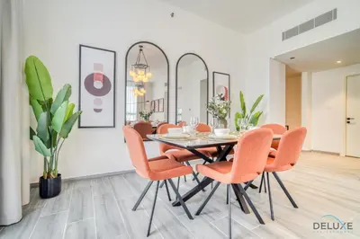 a dining room with a table and orange chairs at Idyllic 2BR with Assistant Room at Mesk 1 Midtown Dubai Production City by Deluxe Holiday Homes in Dubai