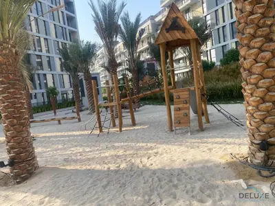 a playground in the sand in front of a building at Idyllic 2BR with Assistant Room at Mesk 1 Midtown Dubai Production City by Deluxe Holiday Homes in Dubai