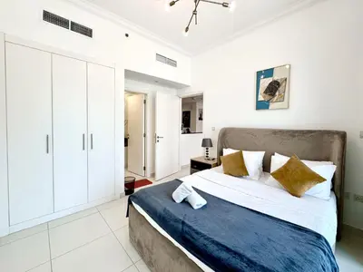 a bedroom with a large bed with white cabinets at Royal Maison Deluxe 2 Br in Executive Bay in Dubai