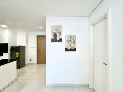 a white hallway with two pictures on a wall at Royal Maison Deluxe 2 Br in Executive Bay in Dubai