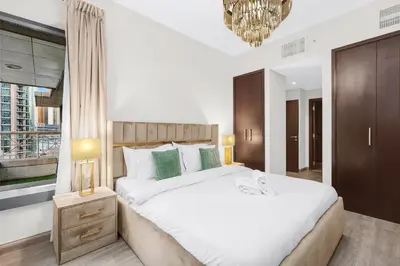 a bedroom with a large white bed and a chandelier at 2BR Burj View with Balcony, Pool, Gym & Walk to Dubai Mall in Dubai