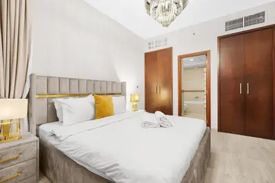 a bedroom with a large white bed and a chandelier at 2BR Burj View with Balcony, Pool, Gym & Walk to Dubai Mall in Dubai