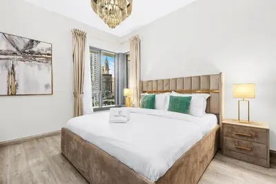 a bedroom with a large bed and a window at 2BR Burj View with Balcony, Pool, Gym & Walk to Dubai Mall in Dubai