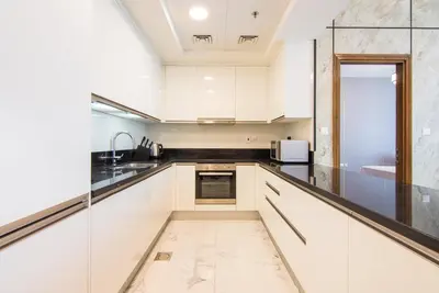a kitchen with white cabinets and a glass wall at Stunning 1BR AL Habtoor City -Meera Tower 1108 in Dubai