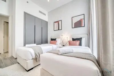 a row of white beds in a room at Suave 2BR with Assistant Room at Mesk 1 Midtown Dubai Production City by Deluxe Holiday Homes in Dubai