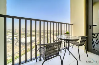 a balcony with a table and chairs and a view at Suave 2BR with Assistant Room at Mesk 1 Midtown Dubai Production City by Deluxe Holiday Homes in Dubai