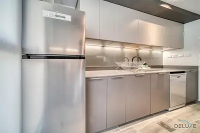a stainless steel refrigerator in a kitchen with white cabinets at Suave 2BR with Assistant Room at Mesk 1 Midtown Dubai Production City by Deluxe Holiday Homes in Dubai