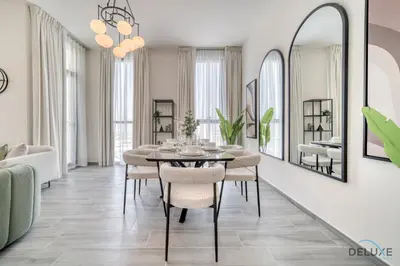 a dining room with a table and chairs and a mirror at Suave 2BR with Assistant Room at Mesk 1 Midtown Dubai Production City by Deluxe Holiday Homes in Dubai