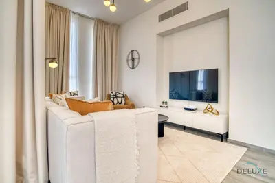 a living room with a white couch and a tv at Charming 2BR with Assistant Room at Mesk 1 Midtown Dubai Production City by Deluxe Holiday Homes in Dubai