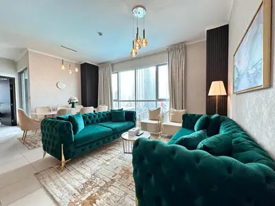 a living room with green couches and a dining room at Durrani Homes - Grand 5BR besides Burj khalifa and Fountain view in Dubai
