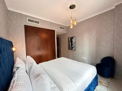 a bedroom with a white bed and a blue chair at Durrani Homes - Grand 5BR besides Burj khalifa and Fountain view in Dubai