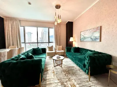 a living room with green couches and a large window at Durrani Homes - Grand 5BR besides Burj khalifa and Fountain view in Dubai
