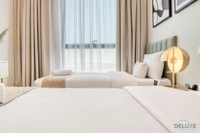 two white beds in a hotel room with a window at Pleasant 2BR with Assistant Room at Mesk 1 Midtown Dubai Production City by Deluxe Holiday Homes in Dubai