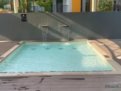 a swimming pool with a water fountain at Pleasant 2BR with Assistant Room at Mesk 1 Midtown Dubai Production City by Deluxe Holiday Homes in Dubai