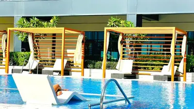 a person sitting in a chair next to a swimming pool at The Shrashi Suites, Dubai Creek Harbour - Paradise on the Island with Dubai Skyline & Waterfront View in Dubai