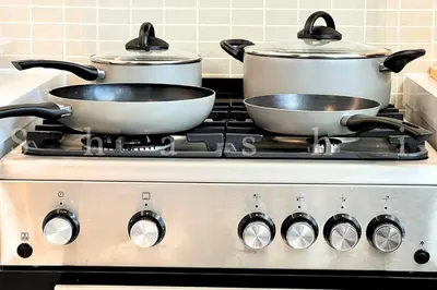 two pots and pans on a stove in a kitchen at The Shrashi Suites, Dubai Creek Harbour - Paradise on the Island with Dubai Skyline & Waterfront View in Dubai