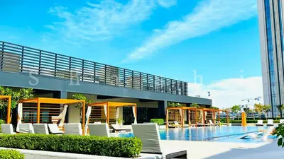 a swimming pool with white chairs and a building at The Shrashi Suites, Dubai Creek Harbour - Paradise on the Island with Dubai Skyline & Waterfront View in Dubai