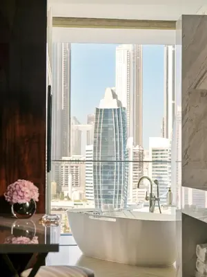a bathroom with a large window with a tub and a city at The Lana - Dorchester Collection in Dubai