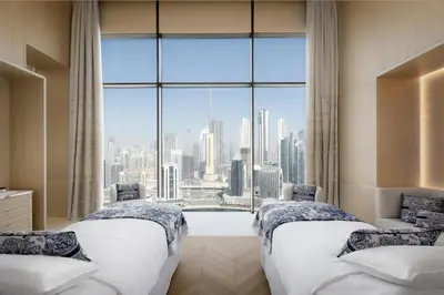 two beds in a room with a large window at The Lana - Dorchester Collection in Dubai