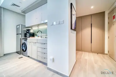 a kitchen with white cabinets and a refrigerator at Striking Studio at Mesk 1 Midtown Dubai Production City by Deluxe Holiday Homes in Dubai