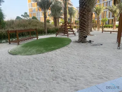 a golf course on the beach with benches and palm trees at Striking Studio at Mesk 1 Midtown Dubai Production City by Deluxe Holiday Homes in Dubai