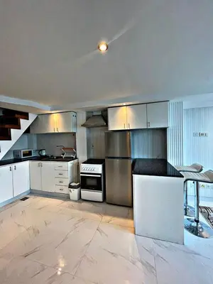 a large kitchen with white cabinets and a stove at Stunning Duplex Studio in JLT in Dubai