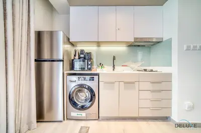 a kitchen with a refrigerator and a washing machine at Splendid Studio at Mesk 1 Midtown Dubai Production City by Deluxe Holiday Homes in Dubai