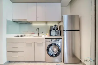 a kitchen with a refrigerator and a washing machine at Prime Studio at Mesk 1 Midtown Dubai Production City by Deluxe Holiday Homes in Dubai