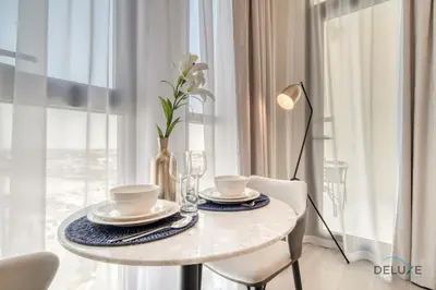 a dining table with a vase of flowers on it at Prime Studio at Mesk 1 Midtown Dubai Production City by Deluxe Holiday Homes in Dubai