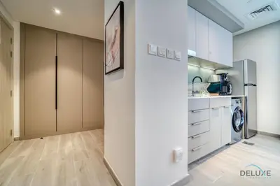 a kitchen with white cabinets and a washer at Prime Studio at Mesk 1 Midtown Dubai Production City by Deluxe Holiday Homes in Dubai