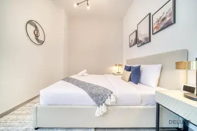 a white bedroom with a bed and a desk at Prime Studio at Mesk 1 Midtown Dubai Production City by Deluxe Holiday Homes in Dubai