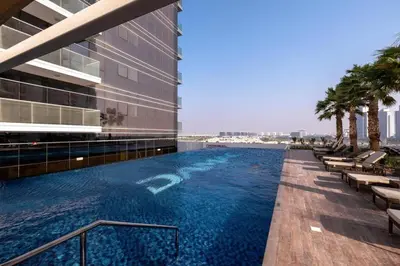 a swimming pool on the side of a building at Tranquil Studio in Damac Hills in Dubai