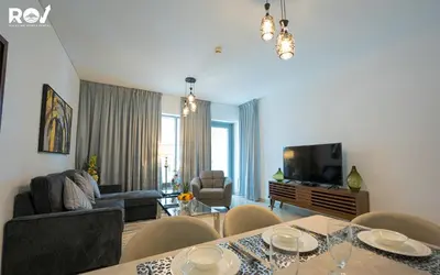 a living room with a table with chairs and a television at Luxury 2 Bedroom Suite with Full Burj Khalifa View in Dubai