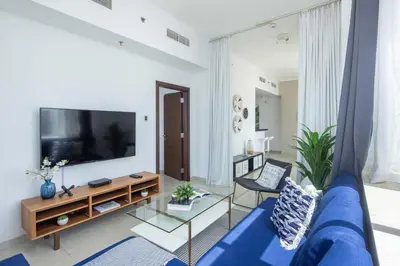 a living room with a blue couch and a tv at Frank Porter - Botanica Tower 1 in Dubai