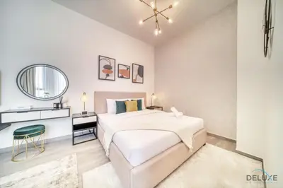 a white bedroom with a large bed and a mirror at Enchanting Studio at Mesk 1 Midtown Dubai Production City by Deluxe Holiday Homes in Dubai