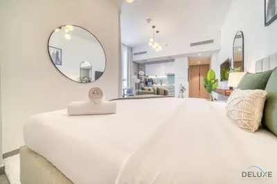 a bedroom with a large white bed and a mirror at Upscale Studio at Mesk 1 Midtown Dubai Production City by Deluxe Holiday Homes in Dubai