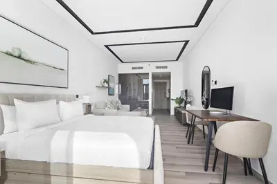 a bedroom with a large white bed and a desk at ALiving Luxury Studio I Nicholas Residence, JVC in Dubai