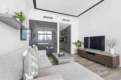 a living room with a couch and a flat screen tv at ALiving Luxury Studio I Nicholas Residence, JVC in Dubai