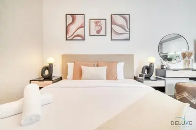 a bedroom with a large white bed and a mirror at Tasteful Studio at Mesk 1 Midtown Dubai Production City by Deluxe Holiday Homes in Dubai