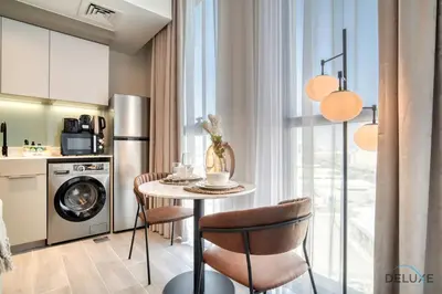 a kitchen with a table and chairs in a room at Tasteful Studio at Mesk 1 Midtown Dubai Production City by Deluxe Holiday Homes in Dubai