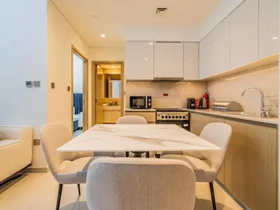 a kitchen with a white table and chairs at Superior 1BR In Burj Royale - Downtown Dubai in Dubai