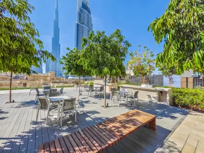 a patio with tables and chairs and trees at Pleasant 1BR in Burj Royale - Downtown Dubai in Dubai