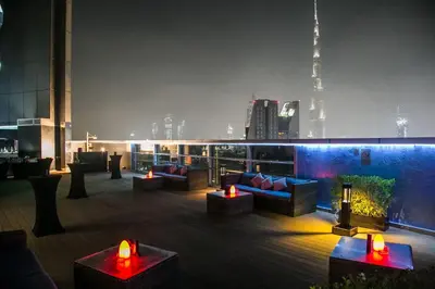 a rooftop deck with couches and tables on a building at Carlton Downtown Hotel in Dubai