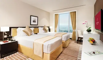 a hotel room with two beds and a large window at Carlton Downtown Hotel in Dubai