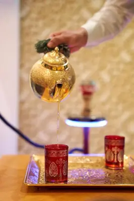 a person pouring water into a tea pot on a table at Carlton Downtown Hotel in Dubai